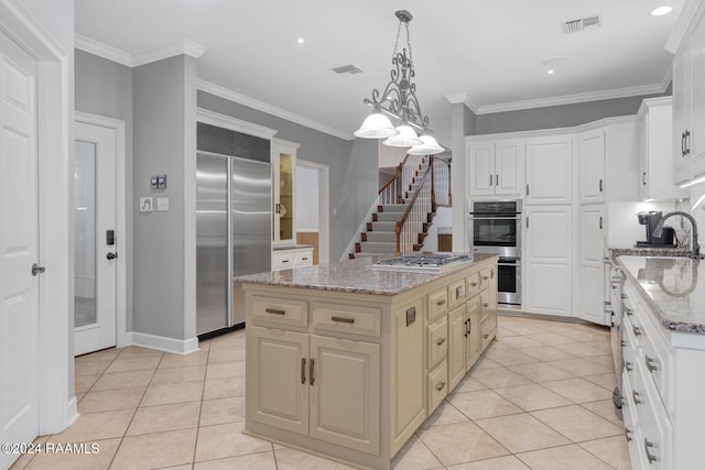 kitchen featuring stainless steel appliances, light tile floors, decorative light fixtures, a center island, and light stone counters