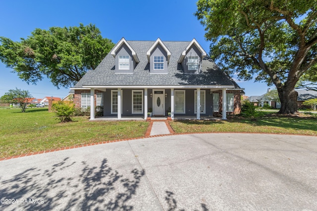 cape cod home with a front yard and a porch