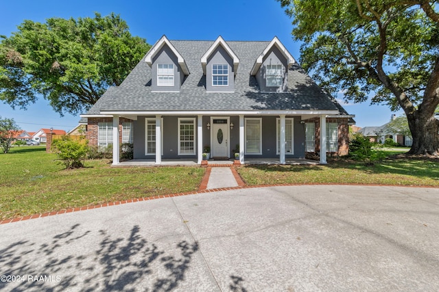 cape cod home with covered porch and a front yard