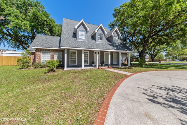 cape cod house featuring covered porch and a front yard