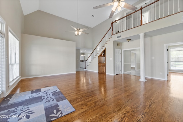 unfurnished living room featuring hardwood / wood-style flooring, ornate columns, and high vaulted ceiling