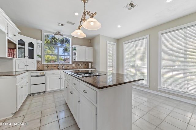 kitchen with white cabinets, decorative backsplash, black cooktop, and a kitchen island