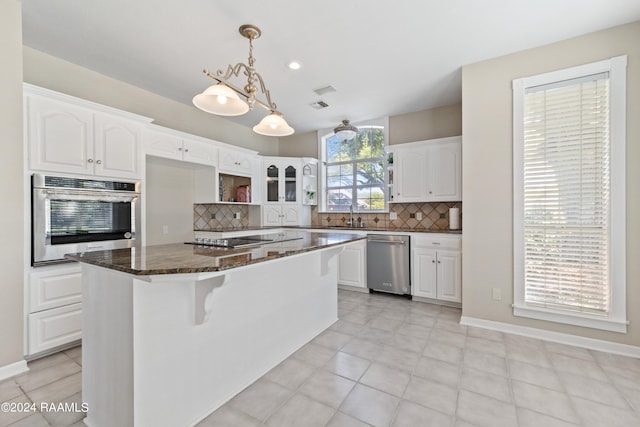 kitchen featuring decorative backsplash, a center island, white cabinets, and stainless steel appliances