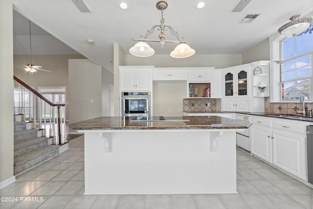 kitchen with white cabinets, dark stone counters, and stainless steel oven