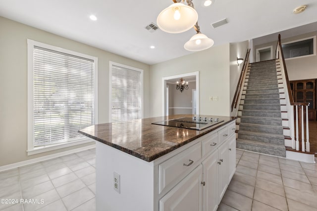 kitchen featuring black electric stovetop, light tile patterned floors, decorative light fixtures, white cabinets, and a center island