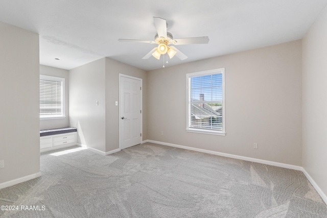 carpeted spare room featuring ceiling fan and a healthy amount of sunlight