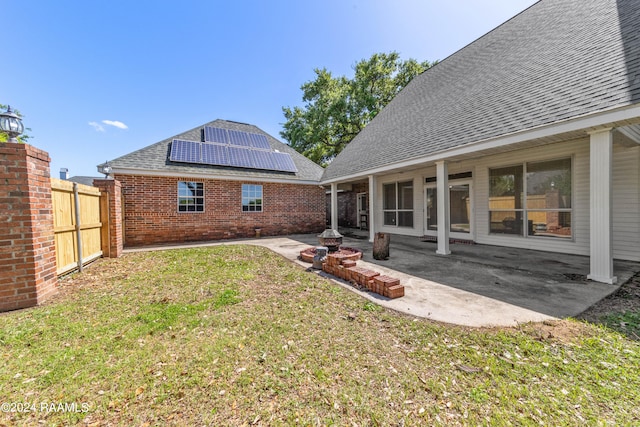 back of property featuring solar panels, a patio, and a yard