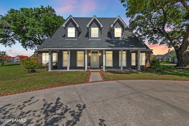 cape cod house with covered porch and a yard