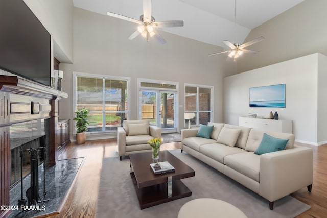 living room featuring wood-type flooring, high vaulted ceiling, and a premium fireplace