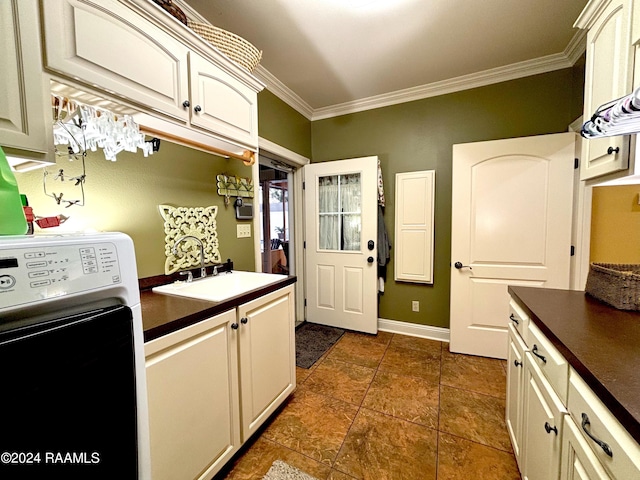 kitchen with white cabinets, dark tile floors, washer / clothes dryer, and ornamental molding