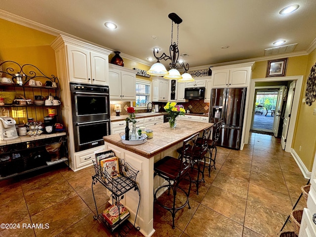 kitchen with a center island, a breakfast bar, backsplash, a notable chandelier, and black appliances