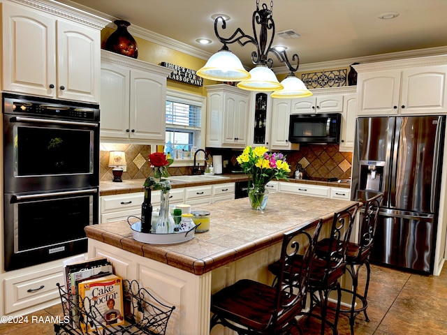 kitchen featuring a kitchen island, a breakfast bar, backsplash, sink, and black appliances