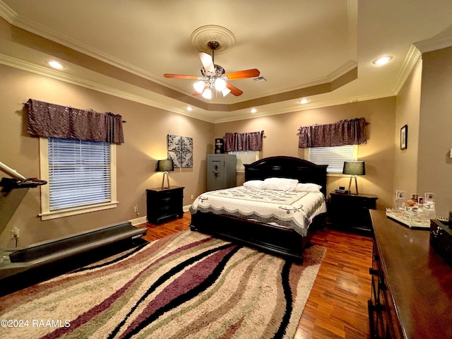 bedroom featuring ornamental molding, wood-type flooring, ceiling fan, and a tray ceiling