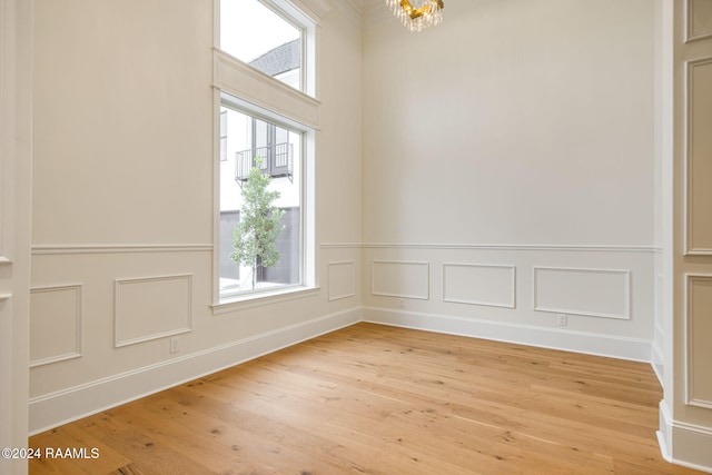 spare room featuring light hardwood / wood-style floors, plenty of natural light, and an inviting chandelier