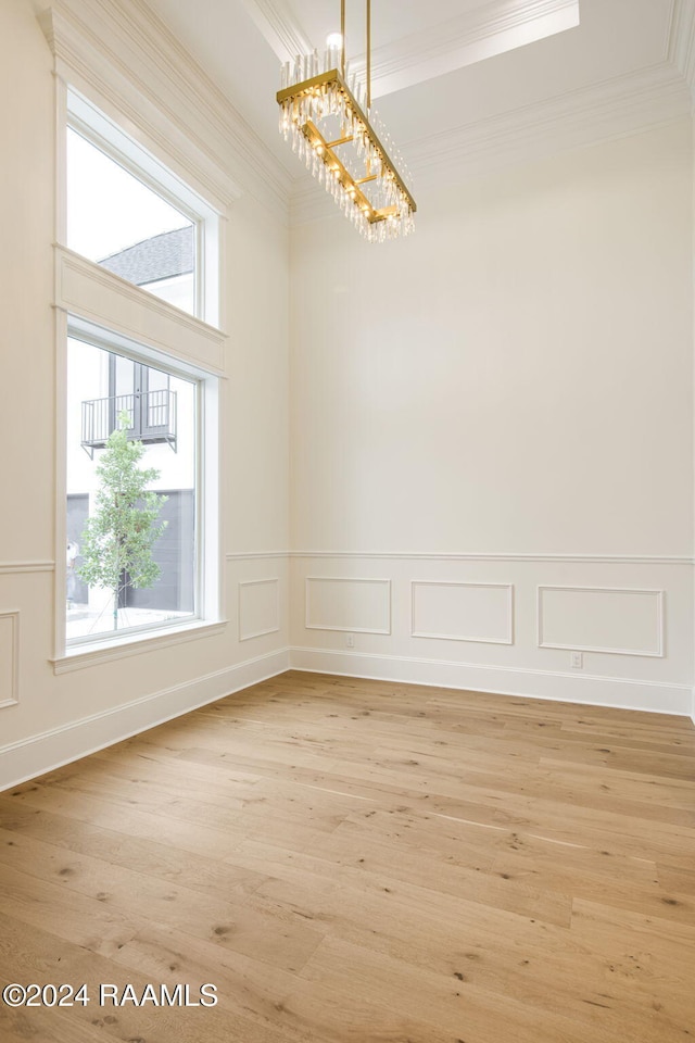 unfurnished dining area featuring ornamental molding, a notable chandelier, and light hardwood / wood-style floors