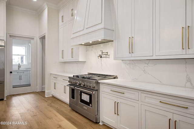 kitchen featuring range with two ovens, white cabinets, backsplash, light hardwood / wood-style flooring, and premium range hood