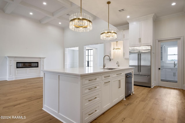 kitchen featuring stainless steel built in refrigerator, a kitchen island with sink, white cabinetry, and sink