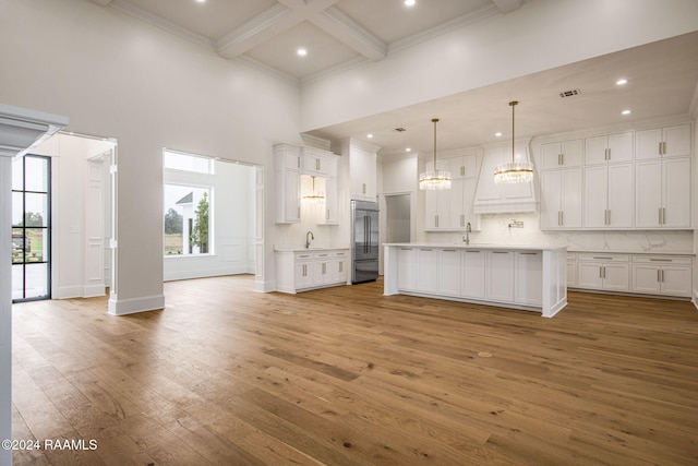 kitchen featuring stainless steel built in refrigerator, an island with sink, light hardwood / wood-style flooring, white cabinets, and pendant lighting