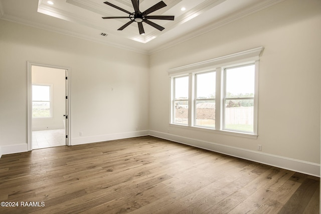 empty room with hardwood / wood-style flooring, ceiling fan, a raised ceiling, and crown molding