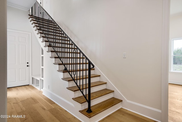 stairs with hardwood / wood-style flooring and crown molding