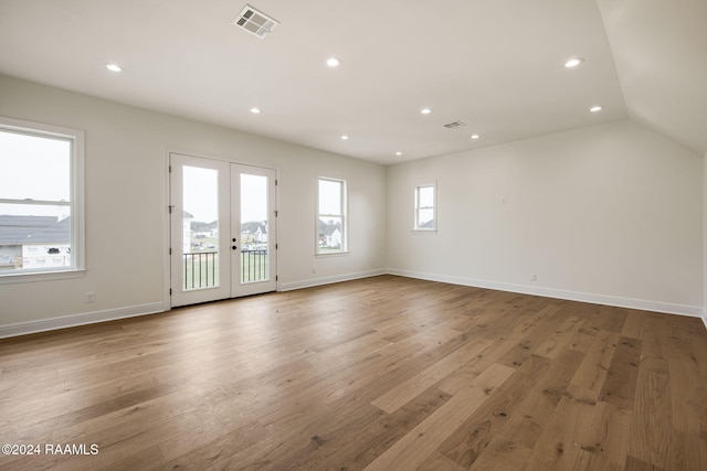 empty room with lofted ceiling, french doors, and light hardwood / wood-style flooring