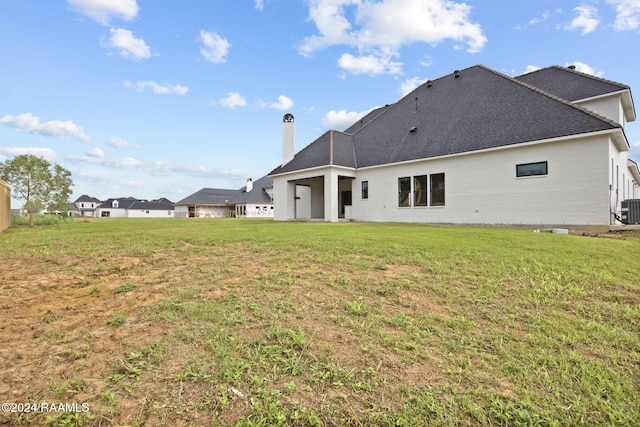 back of property featuring central air condition unit and a lawn