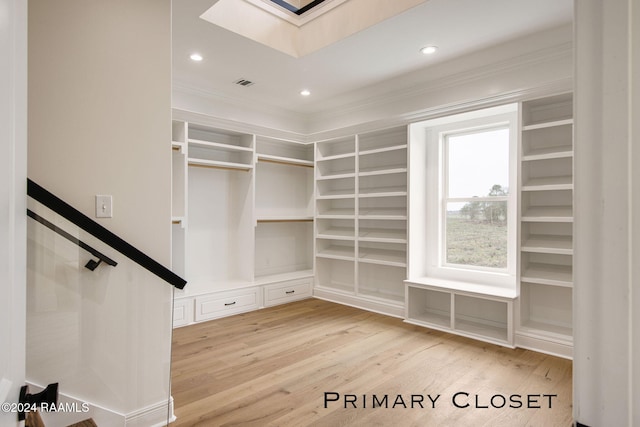 walk in closet with light wood-type flooring and a skylight