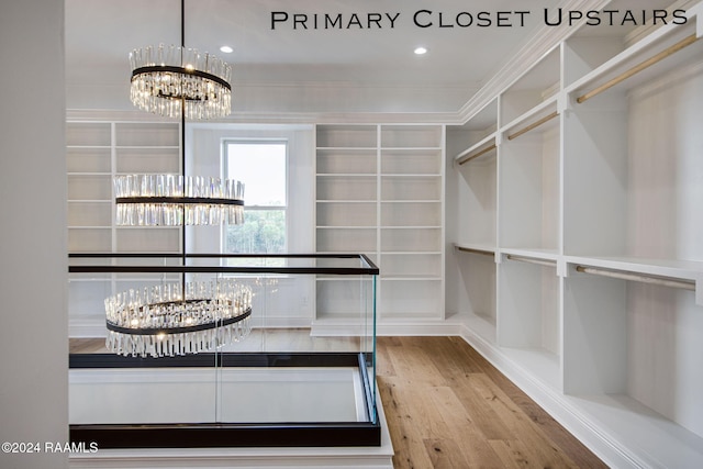 walk in closet with a notable chandelier and light hardwood / wood-style floors