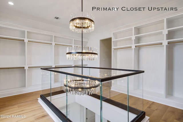 spacious closet featuring hardwood / wood-style floors and a notable chandelier