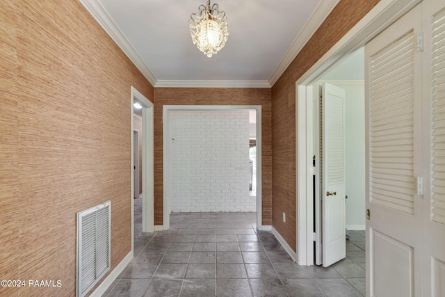 corridor with ornamental molding, a notable chandelier, and dark tile floors