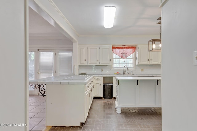 kitchen featuring ornamental molding, backsplash, white cabinetry, and tile countertops