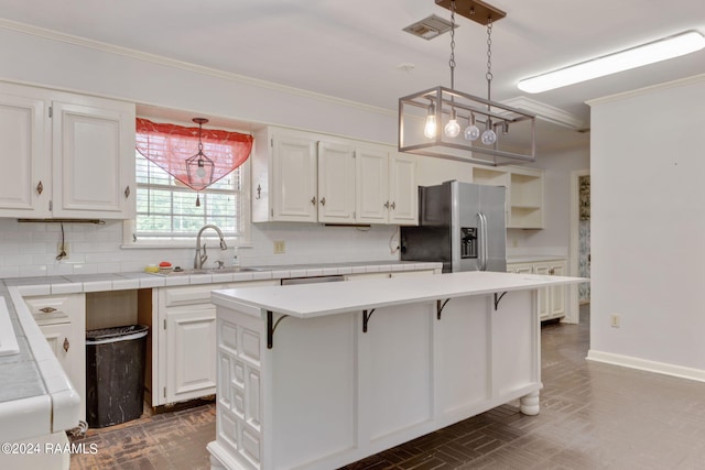 kitchen with tasteful backsplash, decorative light fixtures, stainless steel fridge with ice dispenser, and white cabinetry