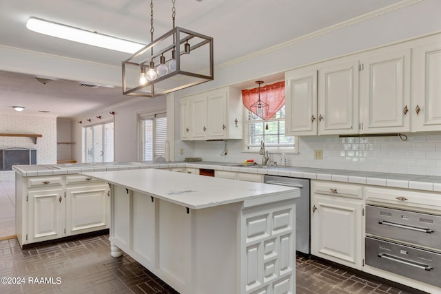 kitchen featuring a brick fireplace, a kitchen island, backsplash, white cabinetry, and pendant lighting