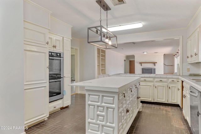 kitchen with appliances with stainless steel finishes, a kitchen island, white cabinets, backsplash, and hanging light fixtures