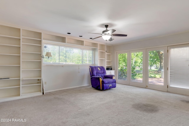 unfurnished room with light colored carpet, ceiling fan, and built in shelves