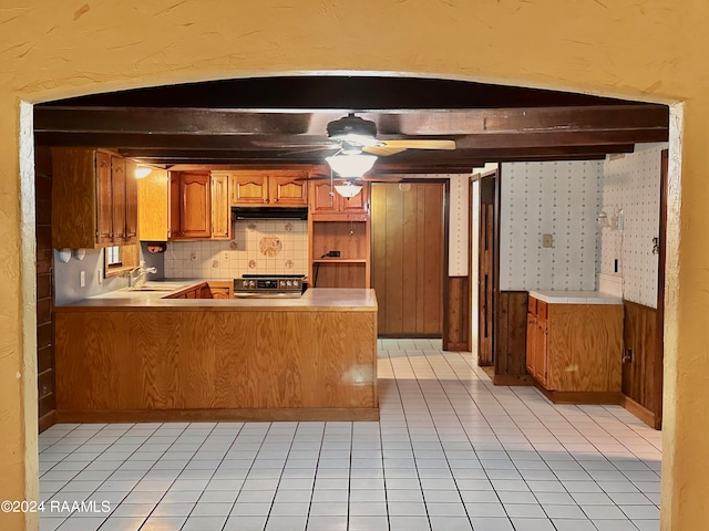 kitchen featuring stainless steel stove, kitchen peninsula, sink, light tile floors, and ceiling fan