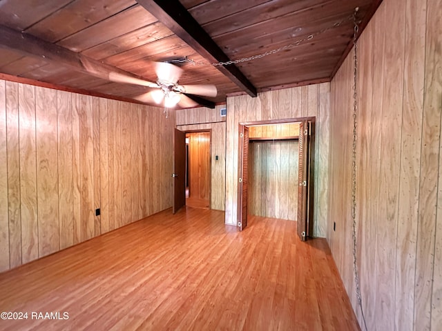 spare room with wooden walls, beamed ceiling, wood ceiling, light hardwood / wood-style floors, and ceiling fan