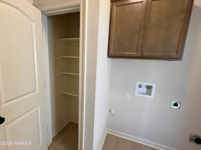 laundry area featuring light hardwood / wood-style floors, hookup for a washing machine, electric dryer hookup, and cabinets