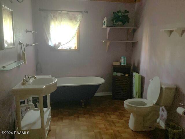 bathroom featuring parquet flooring, toilet, and a wealth of natural light