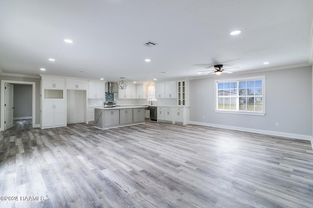 unfurnished living room featuring light hardwood / wood-style floors, ceiling fan, sink, and crown molding