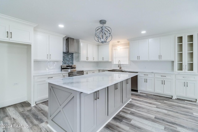 kitchen with wall chimney range hood, hanging light fixtures, stainless steel electric stove, and light hardwood / wood-style flooring