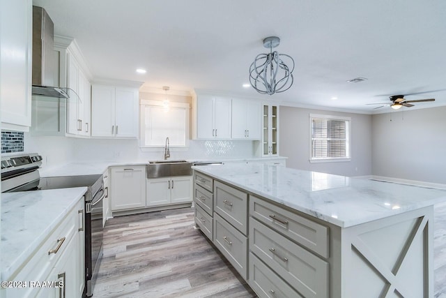 kitchen with electric stove, wall chimney exhaust hood, decorative light fixtures, and a wealth of natural light