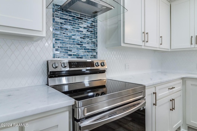 kitchen featuring premium range hood, stainless steel range with electric cooktop, light stone countertops, tasteful backsplash, and white cabinets