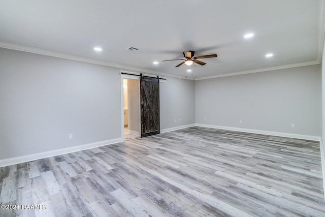 empty room with a barn door, ornamental molding, ceiling fan, and light wood-type flooring