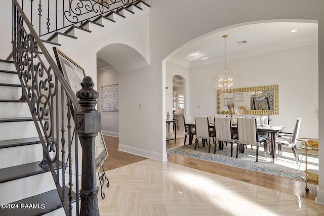 dining space featuring parquet floors, an inviting chandelier, a towering ceiling, and crown molding