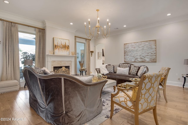 living room with ornamental molding, a chandelier, light wood-type flooring, and a fireplace