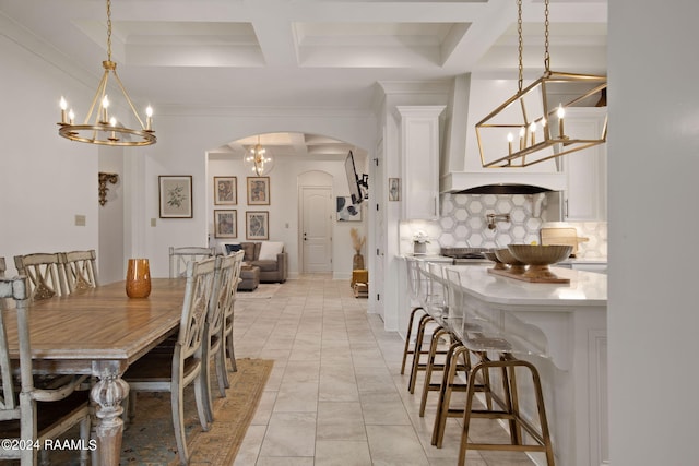 dining area featuring coffered ceiling, beam ceiling, light tile flooring, and a notable chandelier