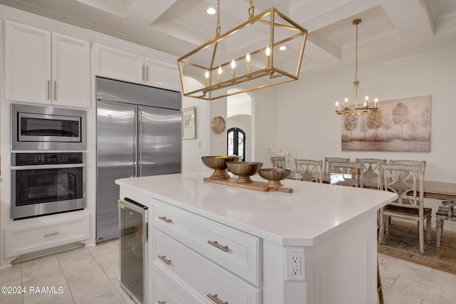 kitchen with decorative light fixtures, coffered ceiling, built in appliances, wine cooler, and a center island