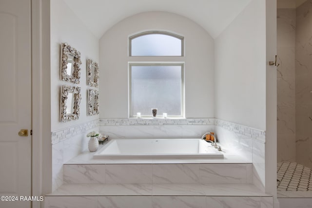 bathroom featuring lofted ceiling and plus walk in shower