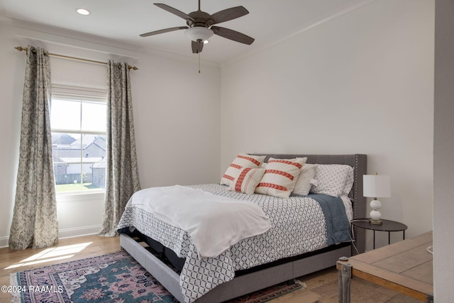 bedroom with hardwood / wood-style floors, ornamental molding, and ceiling fan